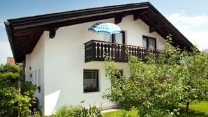 Una casa a due piani con un balcone, una recinzione in legno e un giardino.