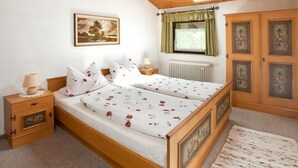 Una camera da letto con un letto in legno, un comodino, un termosifone, una finestra con tende e una porta con pannelli di vetro decorativi.
