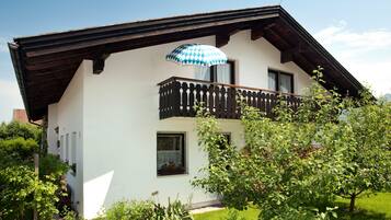 Ein zweistöckiges Haus mit Balkon, Holzzaun und Garten.