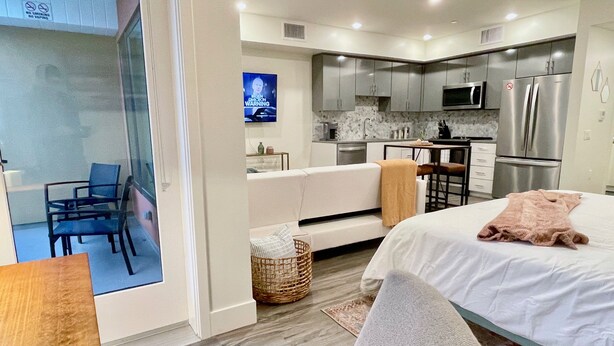 A modern hotel room with a bed, a seating area, a kitchen, and a TV. - Pets Stay Free in Downtown Walnut Creek Condo (Walnut Creek)