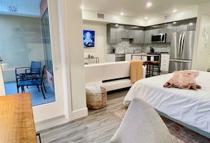 A modern hotel room with a bed, a seating area, a kitchen, and a TV. - Pets Stay Free in Downtown Walnut Creek Condo (Walnut Creek)