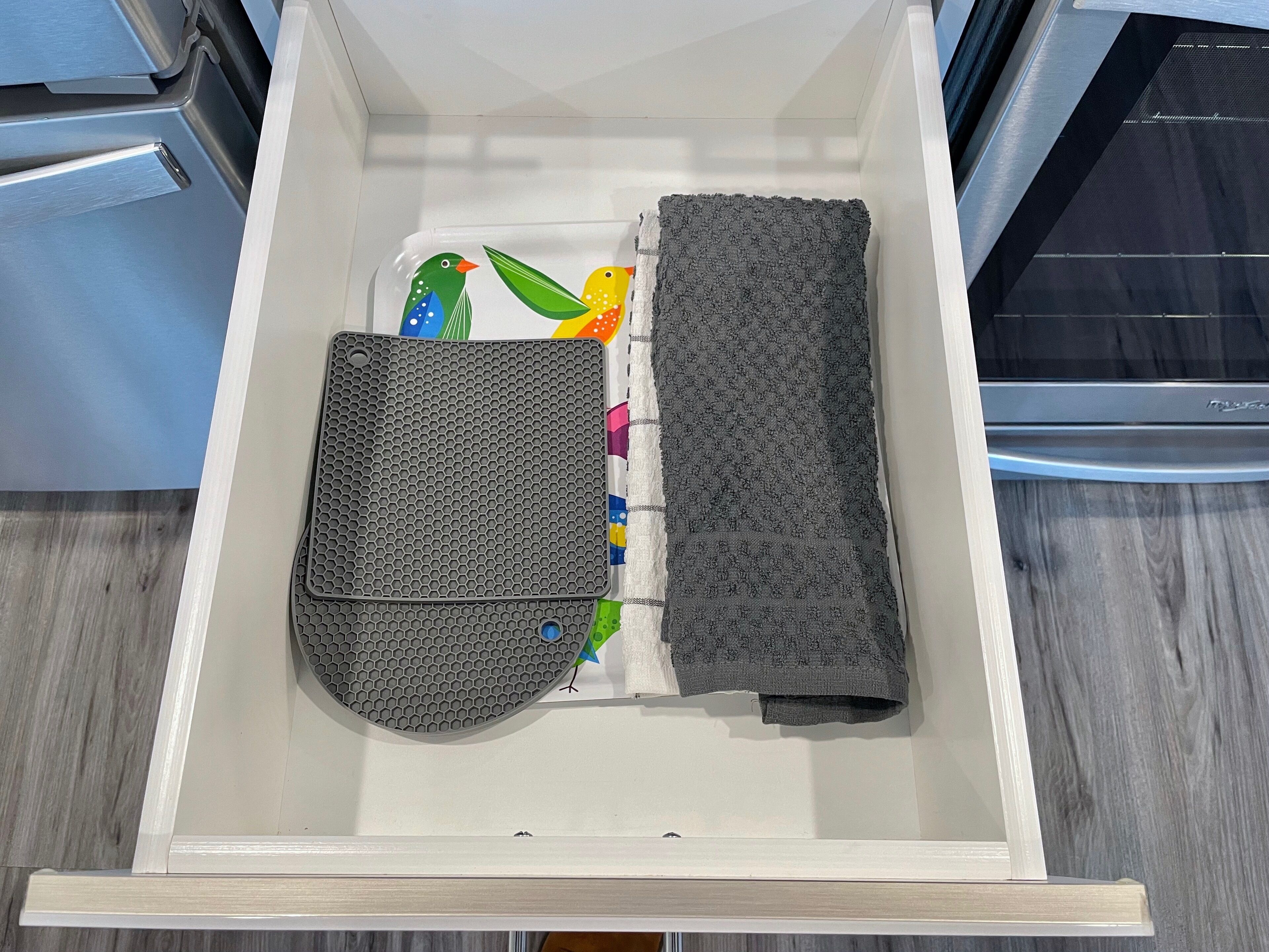 A kitchen drawer with a microwave, a kettle, and a sponge.