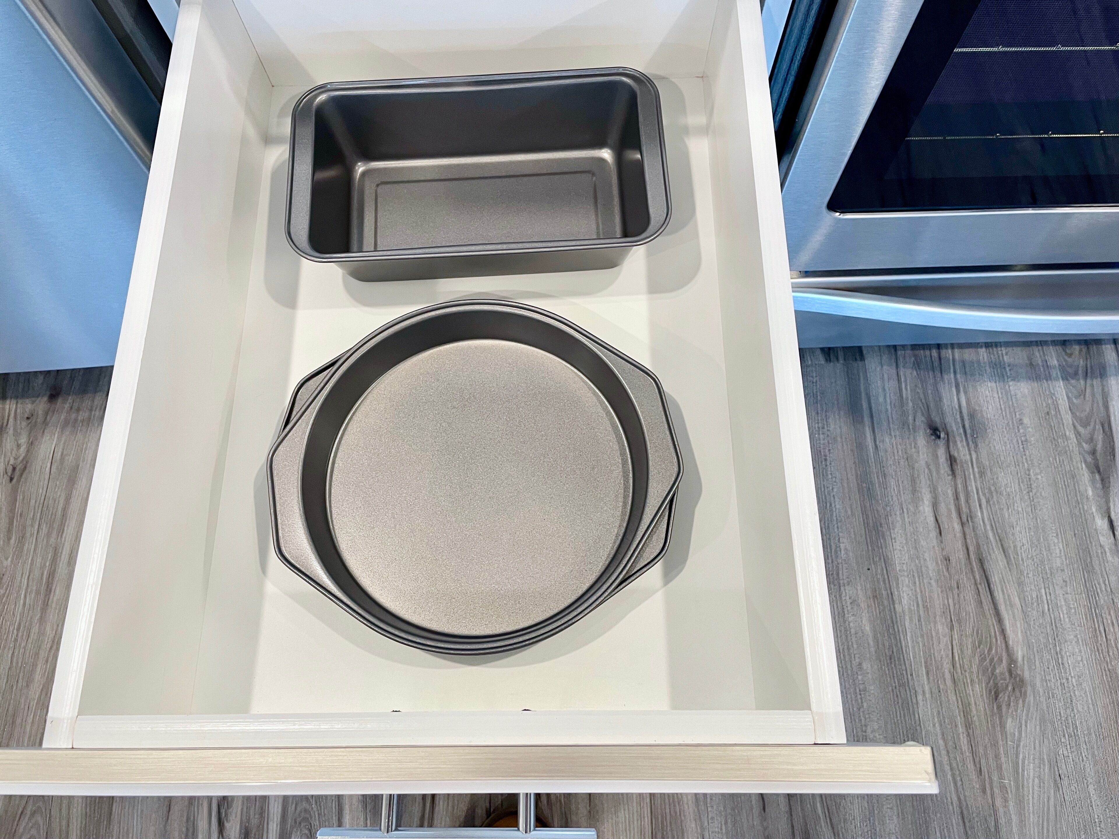 A kitchen drawer with two baking pans and a round baking dish.