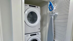 A laundry room with two stacked Whirlpool washing machines and a blue iron hanging on the wall. - Pets Stay Free in Downtown Walnut Creek Condo (Walnut Creek)