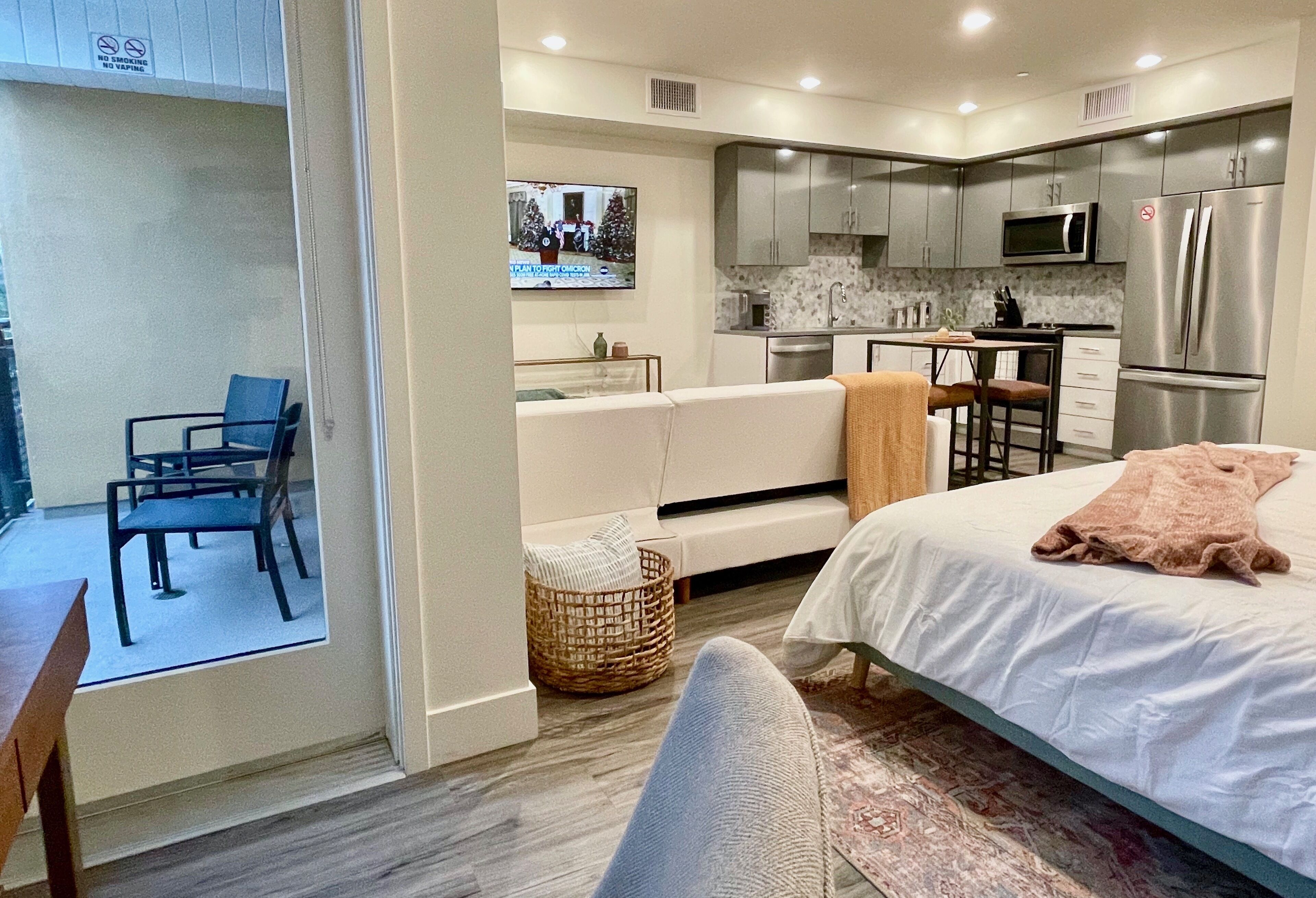 Una habitación de hotel compacta con cama, una pequeña zona de estar, kitchenette y televisor.
