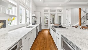 A modern kitchen with white cabinetry, a large island, and a wooden floor. - Pet Friendly WaterColor 4BR Home in the Lake District (Santa Rosa Beach)