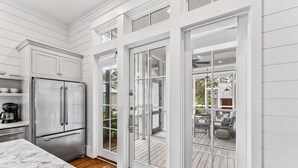 A kitchen with a stainless steel refrigerator, white cabinetry, and a marble countertop. - Pet Friendly WaterColor 4BR Home in the Lake District (Santa Rosa Beach)