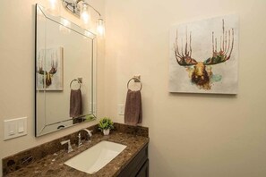 A bathroom with a large mirror, a sink, and two towels hanging on towel rings. - Alpine Retreat - Donner Lake - Walk to West End Beach (Truckee)