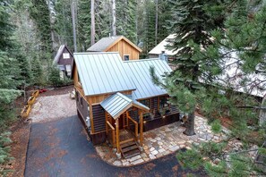 A log cabin with a metal roof, surrounded by dense forest. - Alpine Retreat - Donner Lake - Walk to West End Beach (Truckee)