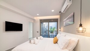 A modern bedroom with a large bed, a flat-screen TV, an air conditioning unit, and a view of a balcony with plants.