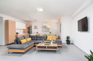 A modern living room with a grey sectional sofa, a wooden coffee table, and a dining area in the background.