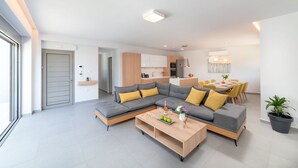 A modern living room with a sectional sofa, a wooden coffee table, and a dining area with yellow chairs.