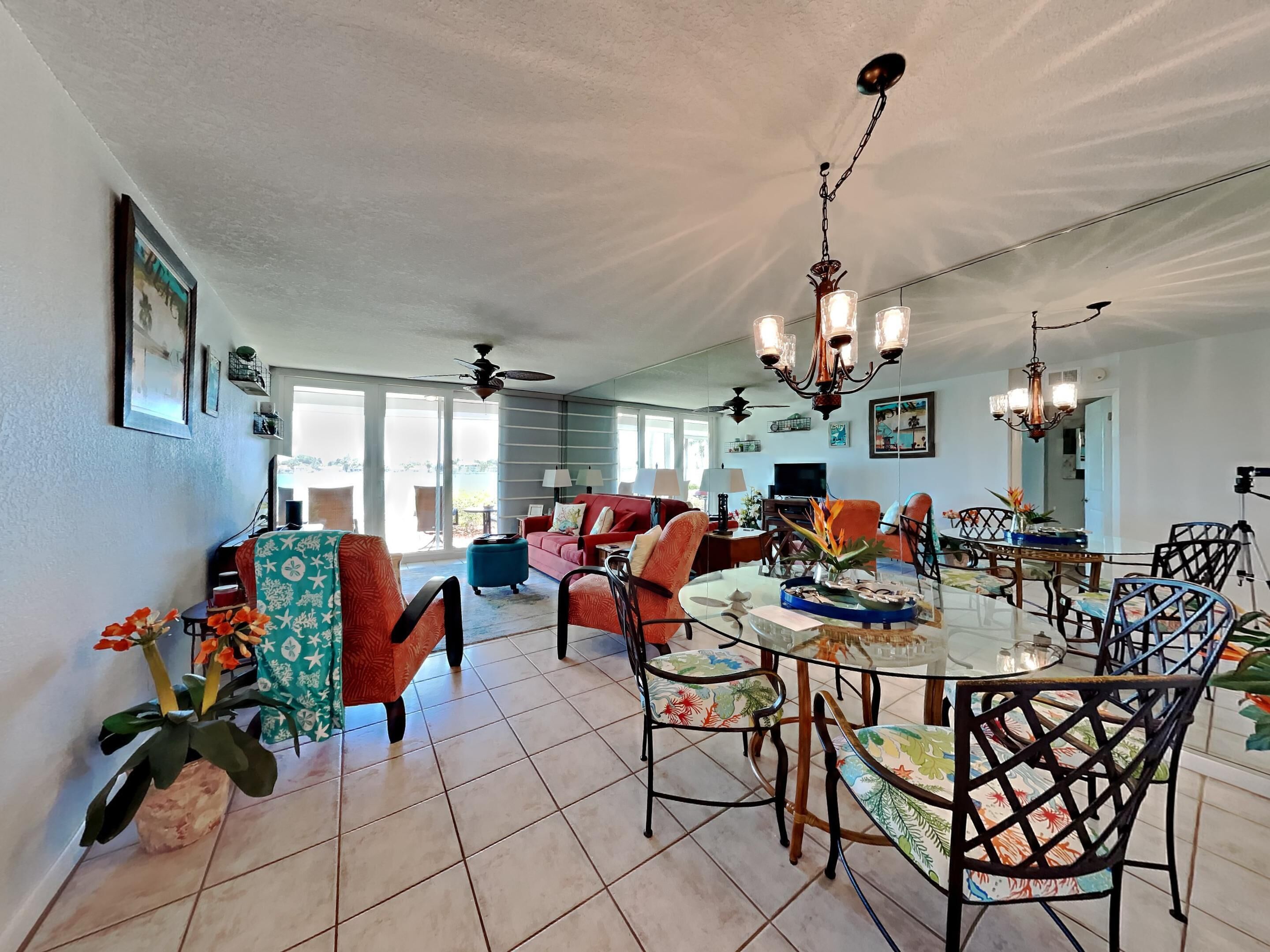 A spacious living area with a dining table, multiple chairs, and a ceiling fan.