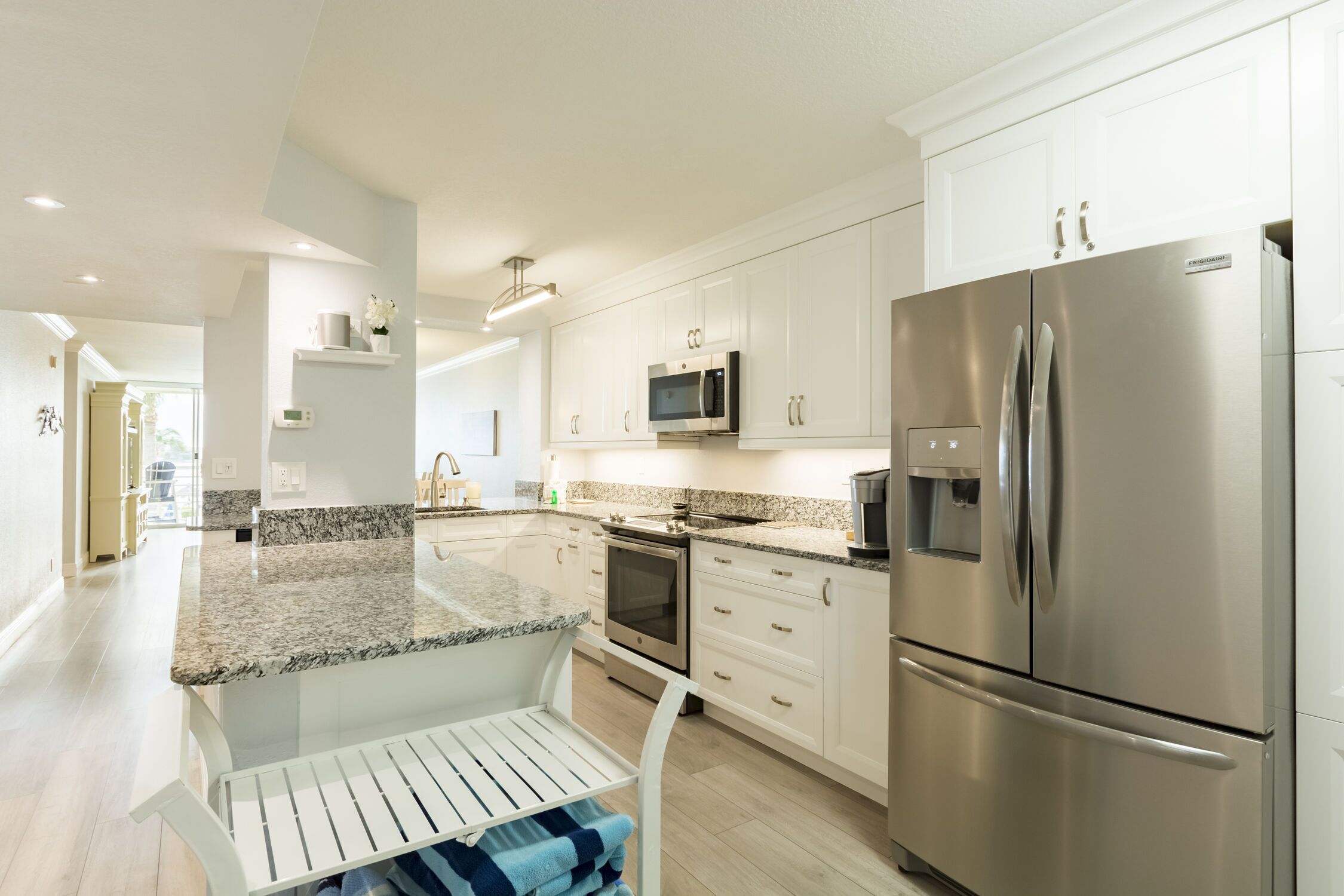 A modern kitchen with white cabinets, stainless steel appliances, granite countertops, and a built-in oven.