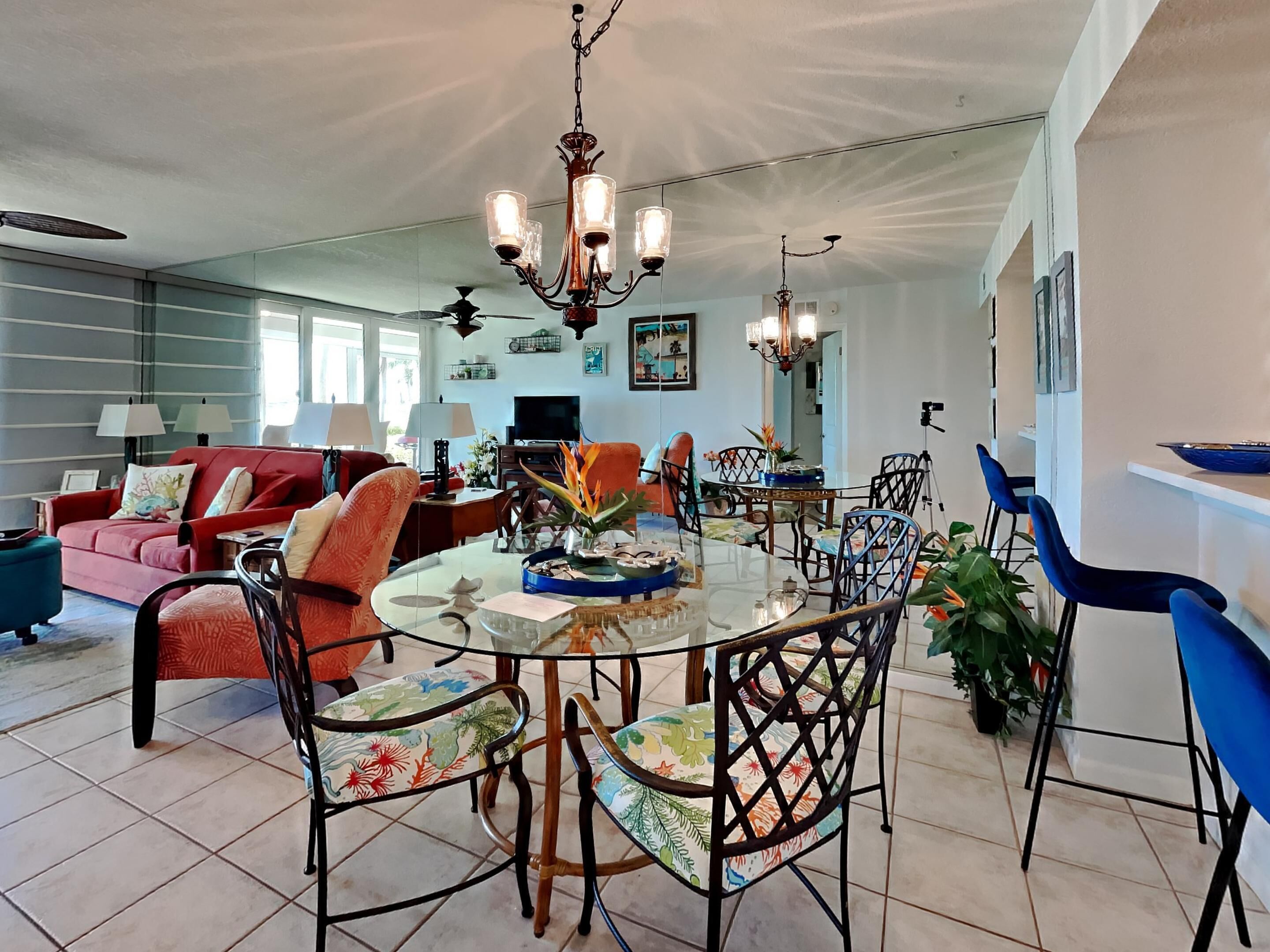 A spacious living room with a red sofa, a dining table with chairs, and a chandelier.