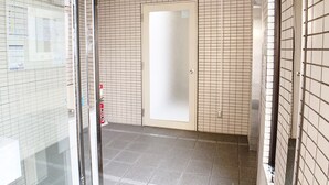 A corridor with tiled walls and a glass door leading to a room. - OUCHI HOTEL Hijiyama (Hiroshima)