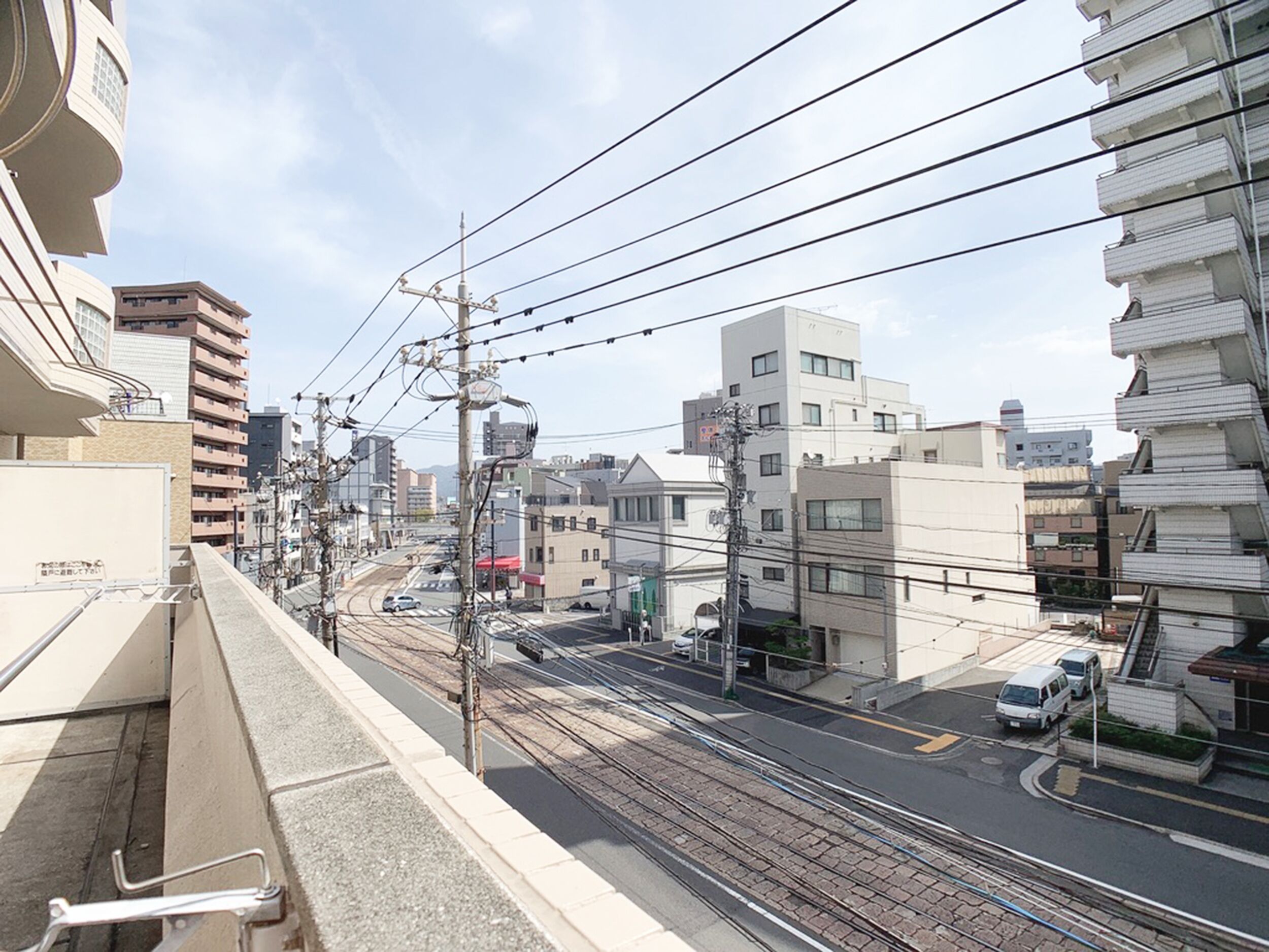Une rue de la ville avec des voies de tramway, des immeubles et des lignes électriques.