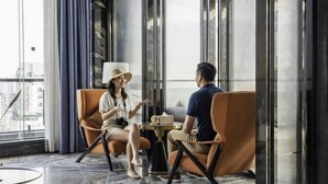 A modern interior with a glass partition, leather chairs, a round table, and a city view. - Ocean Hotel (Phnom Penh)