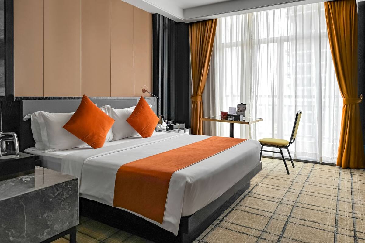 Ein Hotelzimmer mit Bett, Schreibtisch, Stuhl und einem kleinen Tisch mit einer Speisekarte.