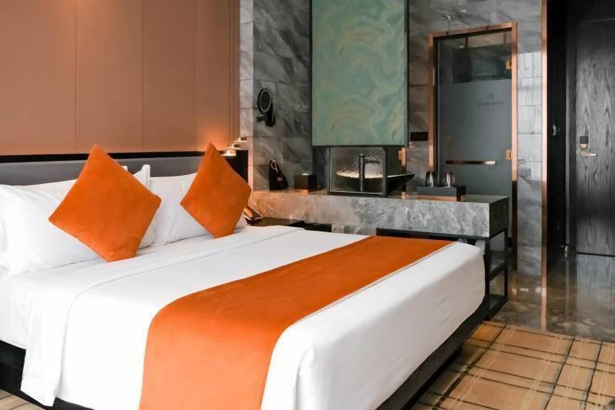 Ein Hotelzimmer mit Bett, Nachttisch, Spiegel und Tür.