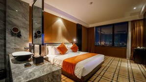 A modern hotel room with a large bed, a marble bathroom sink, and a city view through the window. - Ocean Hotel (Phnom Penh)
