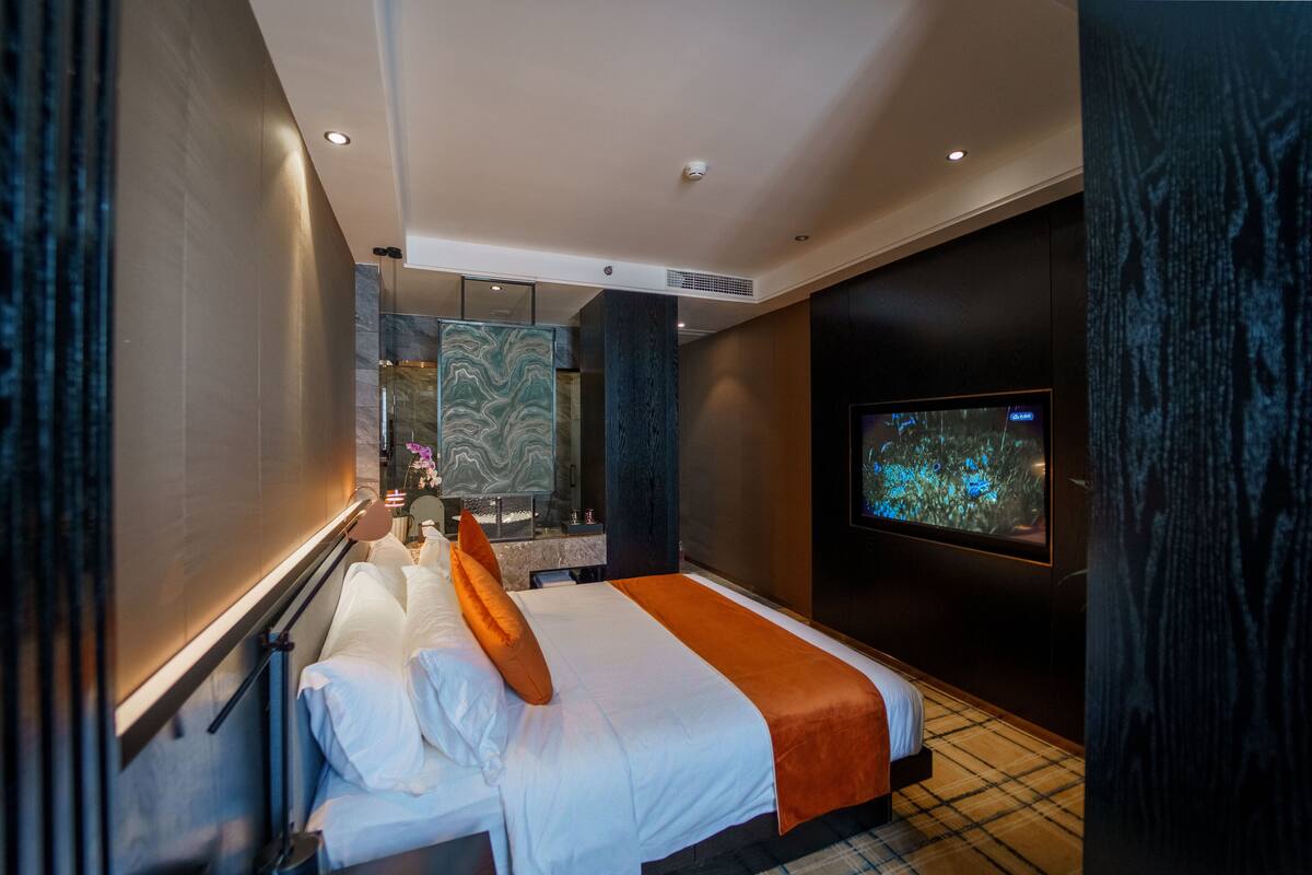 Ein modernes Hotelzimmer mit einem großen Bett, einem Fernseher und einer Marmorwand.