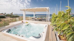 A hot tub with a wooden deck, a covered seating area, and a view of the ocean. - Protaras Holiday Villa Wp4 (Paralimni)