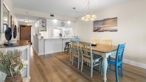 A modern kitchen with white cabinetry, a wooden dining table, and blue chairs.
