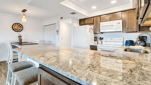 A kitchen with a granite countertop, white cabinets, and a stainless steel sink. - 🌅 Gulf Gate Resort Unit 206 – Updated Bay View Condo with Coastal Charm for Up to 4 Guests (St Pete Beach)