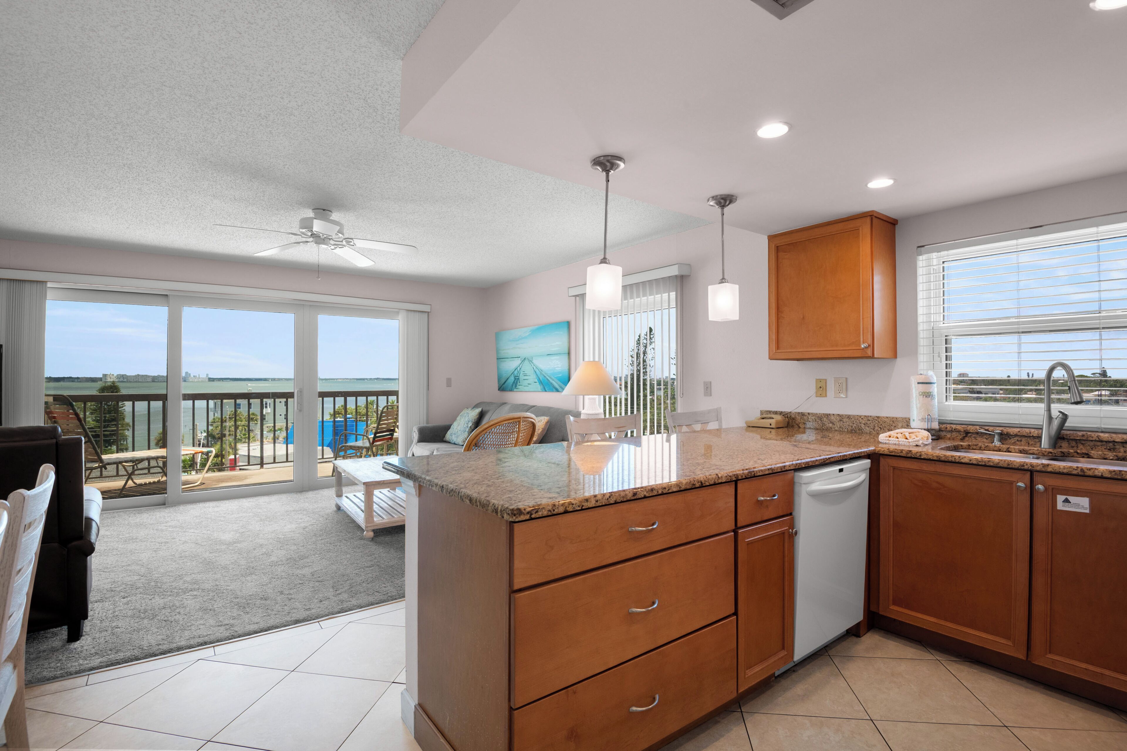 A modern kitchen with a large island, wooden cabinets, and a view to a balcony.