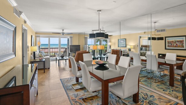 A spacious hotel room with a balcony, a dining area with a table and chairs, and a large window offering a view of the ocean. - 🌅 Unit 102 at Gulf Gate – Renovated Luxury with Gulf Views for Up to 6 Guests (St Pete Beach)