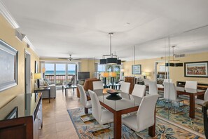 Amplia habitación de hotel con balcón, zona de comedor con mesa y sillas, y un gran ventanal con vistas al océano.