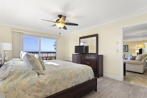 Une chambre à coucher avec un lit, une commode, une télévision et un balcon offrant une vue.