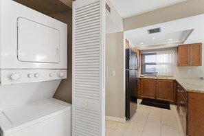 A compact kitchen with a built-in washer and dryer, wooden cabinets, and a refrigerator.