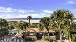 Rantalomakeskus, jossa on aurinkotuoleja, palmuja ja näkymä merelle.