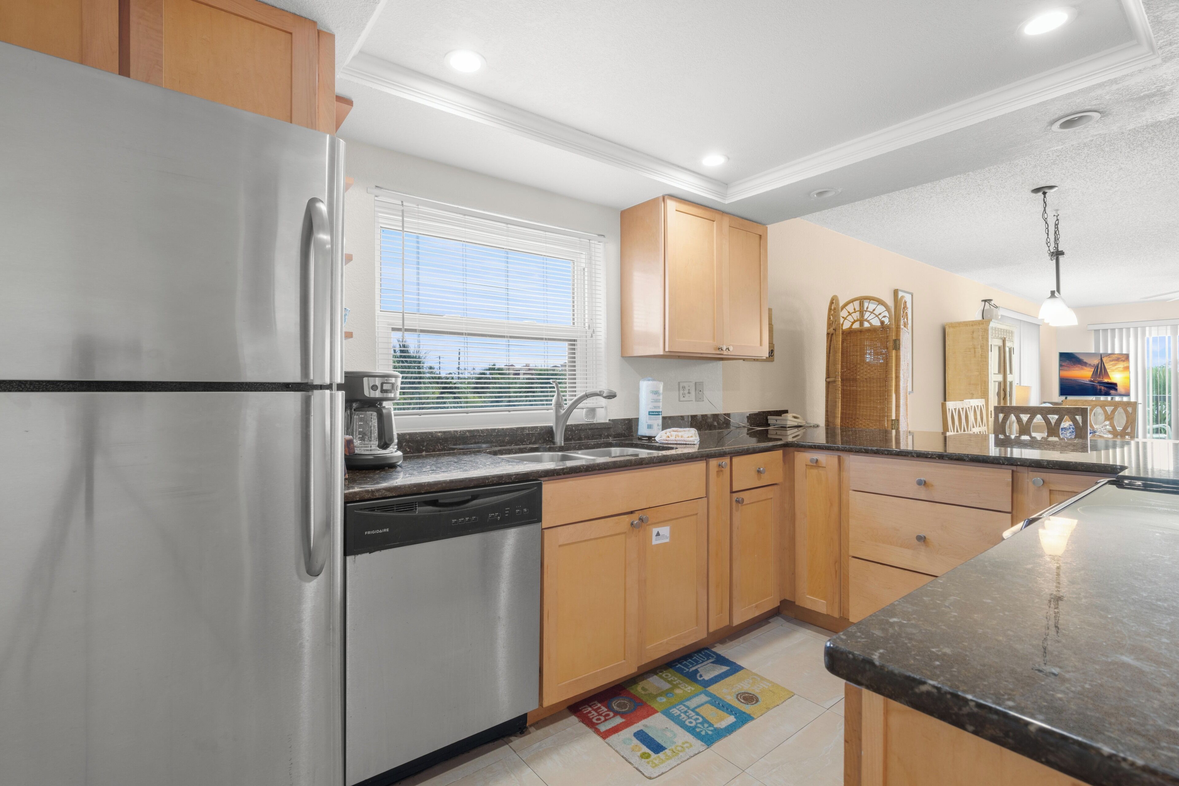 A modern kitchen with stainless steel appliances, wooden cabinets, and a large window.