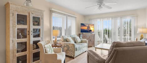 A living room with a sofa, armchairs, a cabinet, and a television.