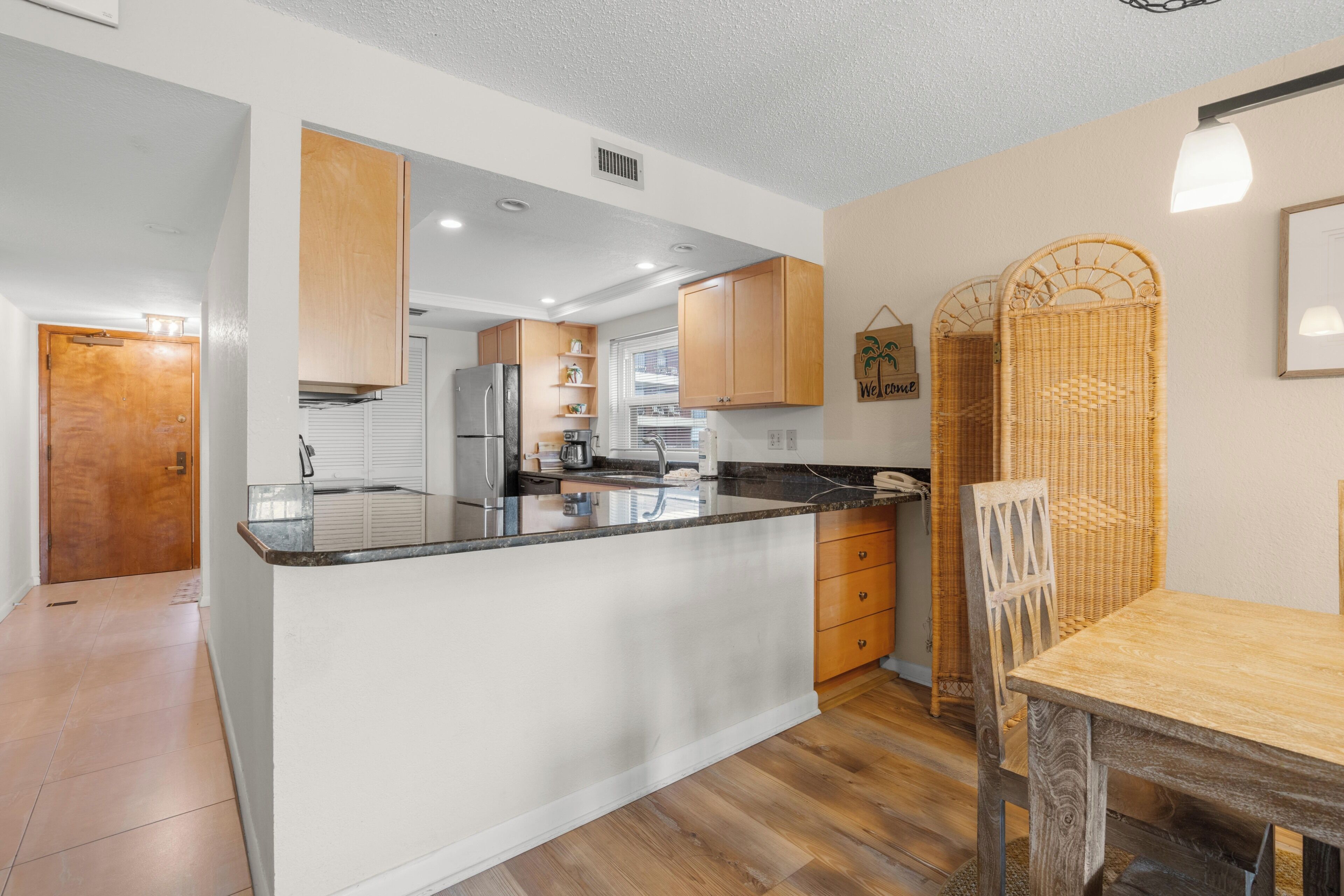 Een moderne keuken met houten kasten, een centraal eiland en een eethoek met een houten tafel en stoelen.