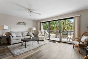 Relax in this serene living space with a sliding door leading to a tranquil outdoor area and a view of palm trees.