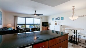 Eine moderne Küche mit einer großen Kochinsel, einem Essbereich mit rundem Tisch und Stühlen sowie ein Balkon mit Aussicht.