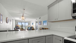 A kitchen with white cabinetry, a stainless steel oven, and a pendant light. - !!!Newly Updated, Throughout!!! Gulf Gate 305 | Bay View Family Escape (St Pete Beach)