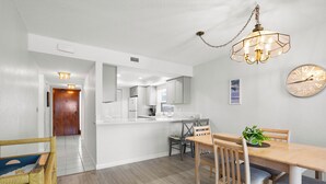 A modern kitchen with white cabinets, a dining table with chairs, and a chandelier. - !!!Newly Updated, Throughout!!! Gulf Gate 305 | Bay View Family Escape (St Pete Beach)