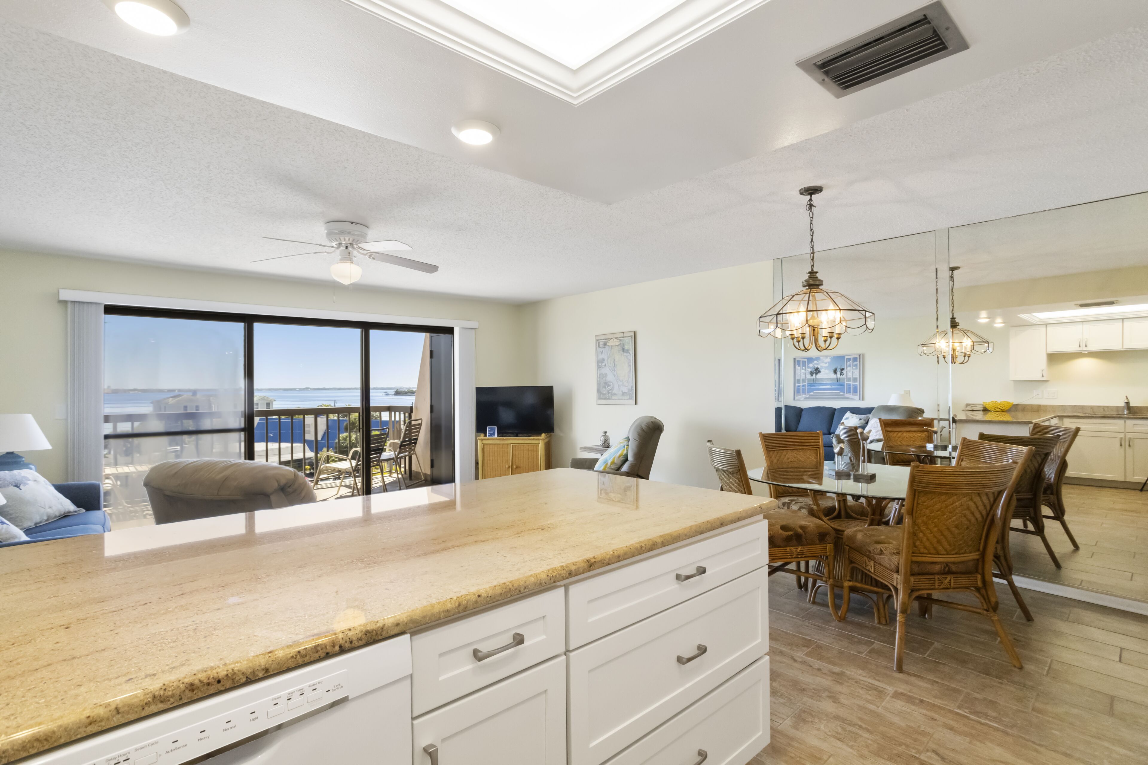 A modern kitchen with a large island, dining area with chairs, and a view of the ocean.