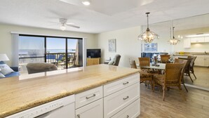 A modern kitchen with a large island, dining area with chairs, and a view of the ocean.