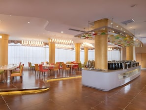 Un comedor moderno con una barra central, diversas opciones de asientos y un techo decorativo.