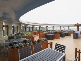 Un salón en la azotea con asientos al aire libre, una zona de bar y vistas al horizonte de la ciudad.