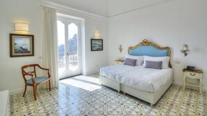 A bedroom with a bed, a chair, a nightstand, and a window with curtains.