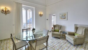 A room with a glass table, chairs, a sofa, and a radiator.