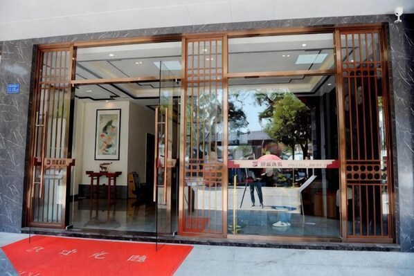 A hotel entrance with a red carpet, glass doors, and a view of the interior. - Fortune Hotel (Taining)
