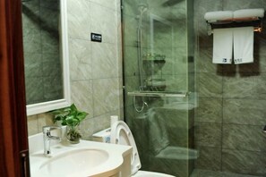 A bathroom with a glass-enclosed shower, a sink with a mirror, and a toilet. - Fortune Hotel (Taining)